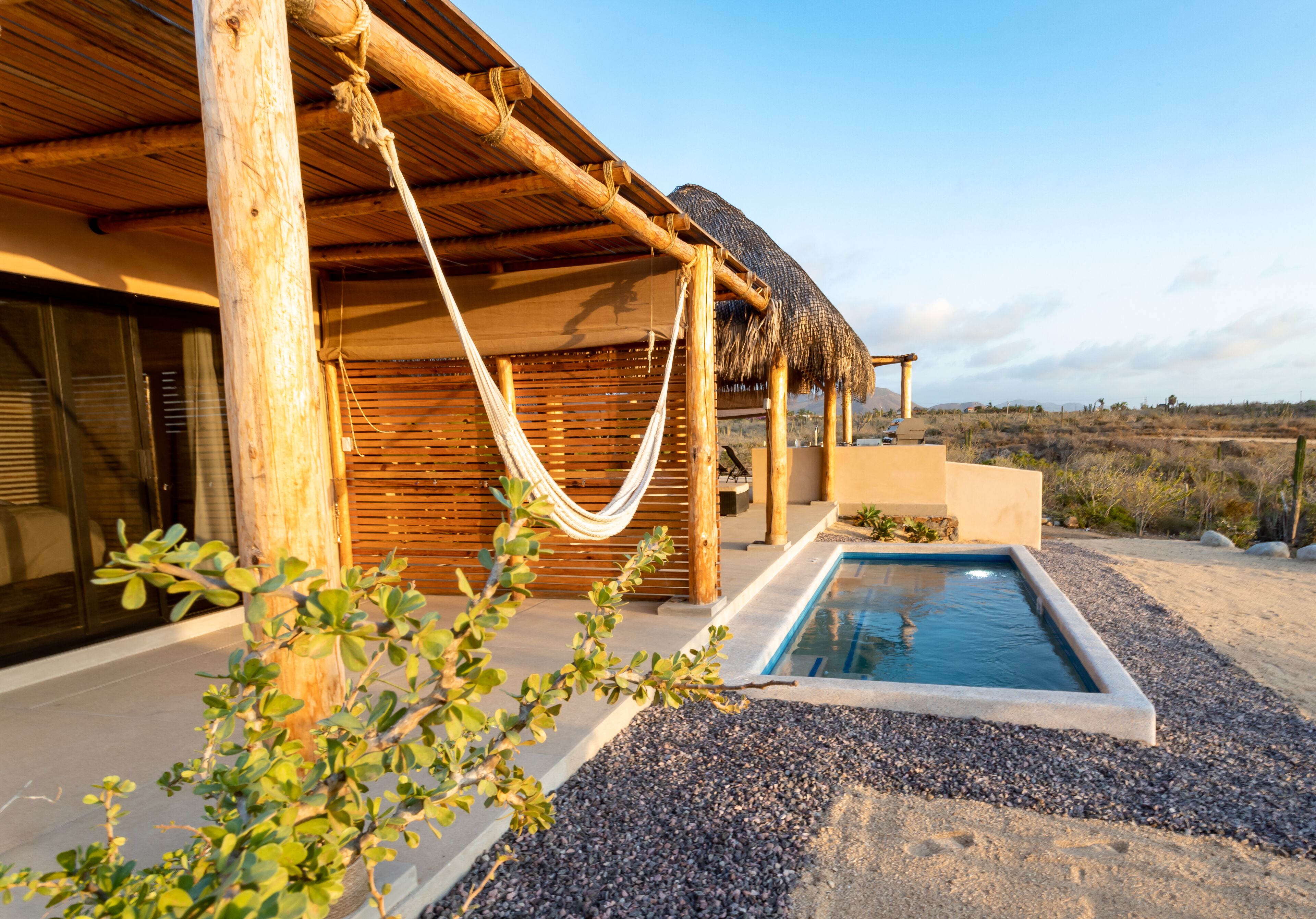 Un espace piscine agrémenté d’une pergola en bois et d’un hamac.
