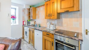A compact kitchen with wooden cabinets, a built-in microwave, a stove, and a washing machine.