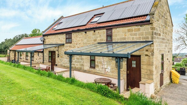 A stone building with a sloped roof and solar panels.