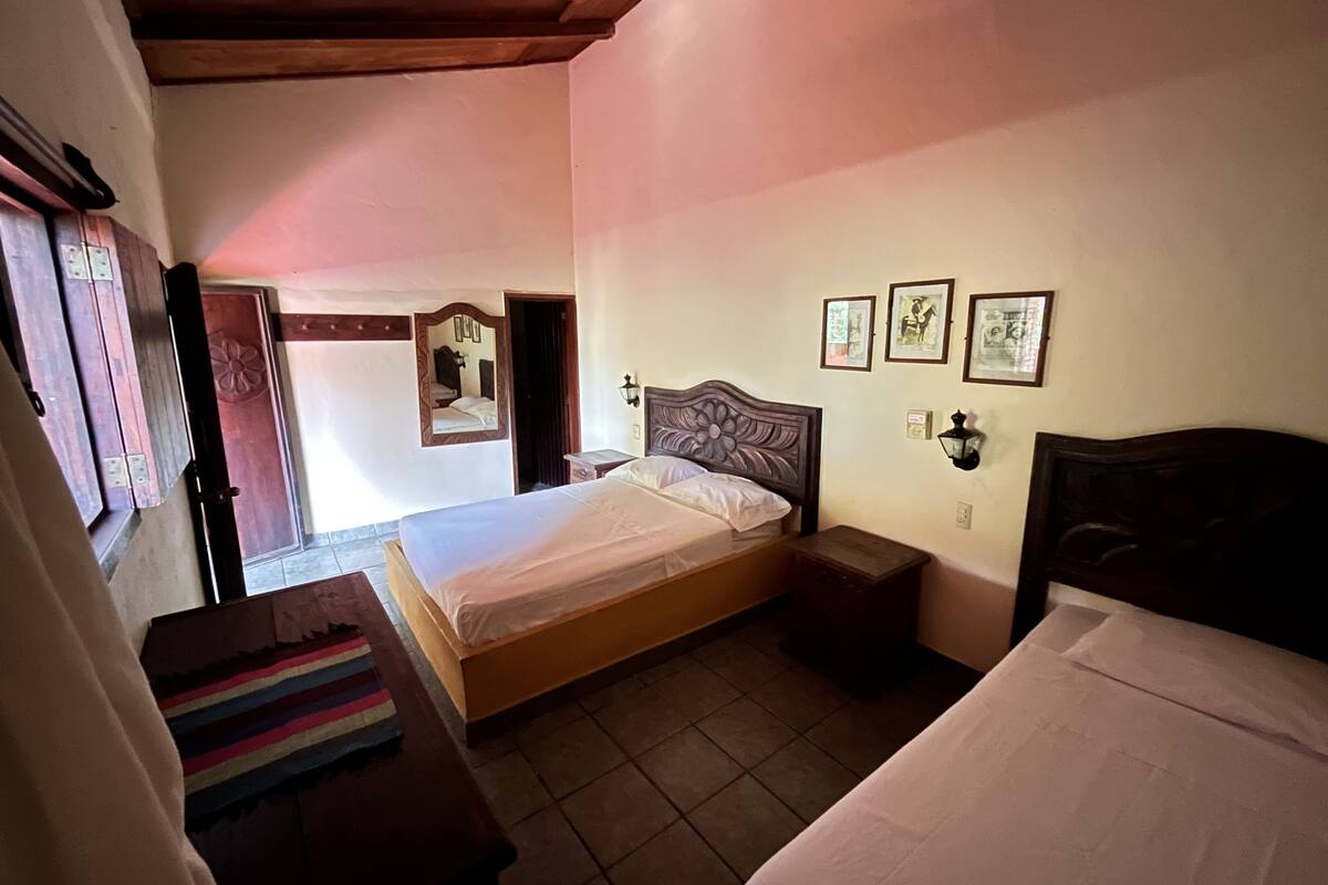 A bedroom with a single bed, a nightstand, a dresser, and a mirror.