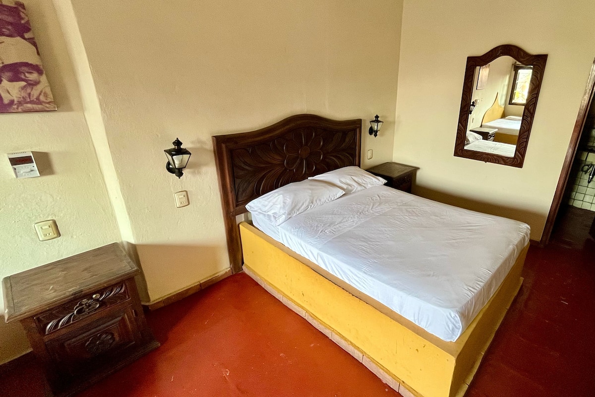 A single bed with a wooden headboard in a room with a red carpet.