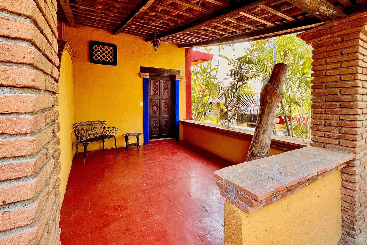 A room with a red floor, a wooden ceiling, a yellow wall, and a wooden door.