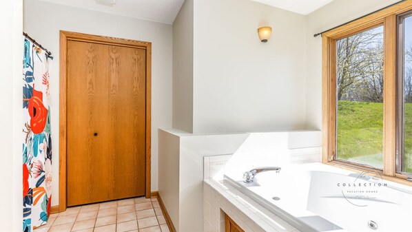 A bathroom with a large window, a wooden door, and a white sink.
