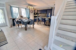 A dining area with a table set for four, a kitchen with modern appliances, and a staircase leading to another level.