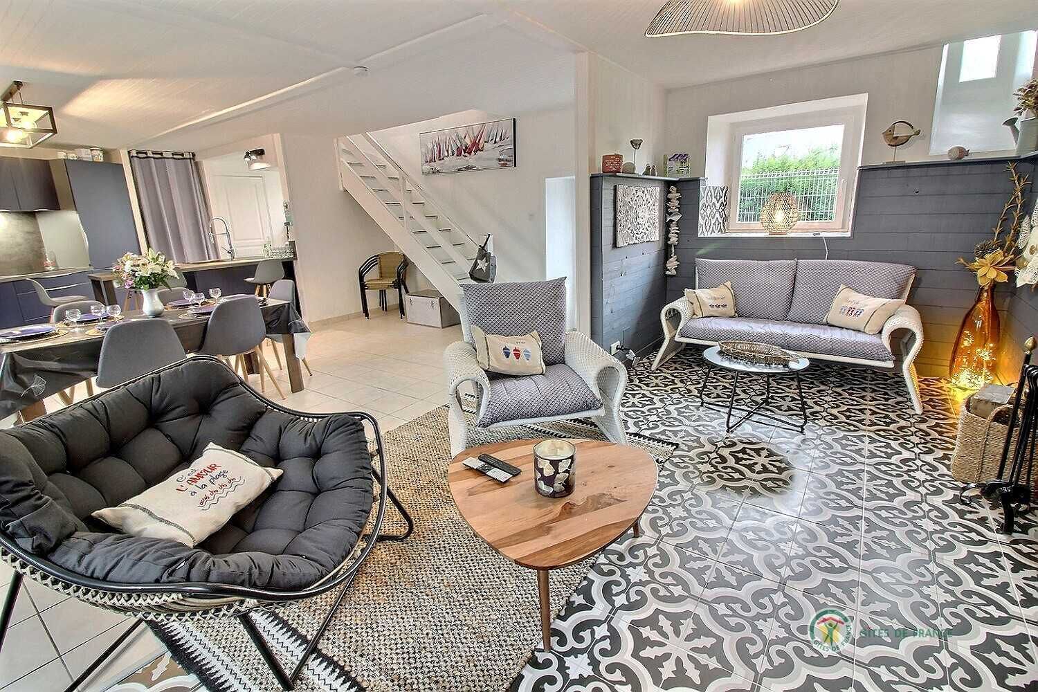 Ett modernt vardagsrum med en soffa, en fåtölj och ett soffbord. En trappa leder upp till ett annat våningsplan.