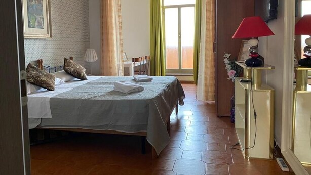 A hotel room with a bed, a desk, a chair, a lamp, and a television. - Milazzo Luxury Home (Rome)