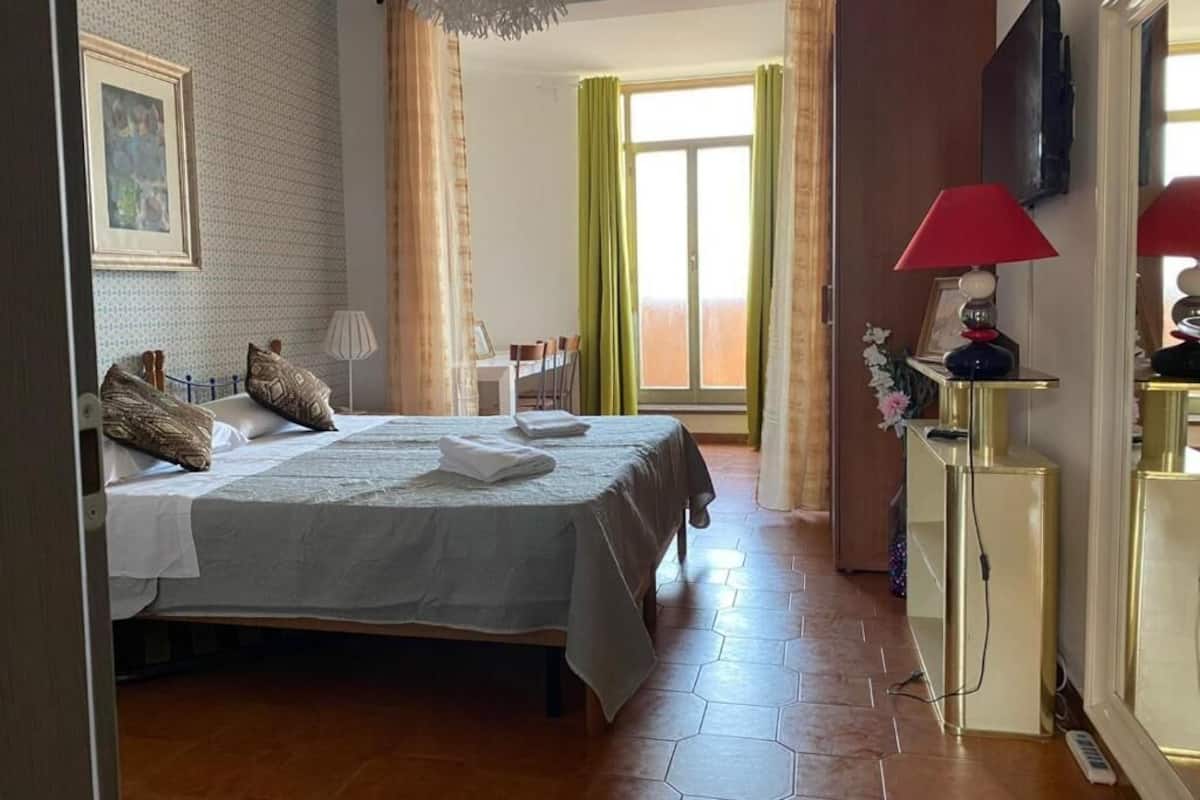A hotel room with a bed, a desk, a chair, a lamp, and a television.