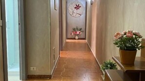 A hallway with hexagonal patterned flooring, a wall-mounted decorative piece, and a potted plant on a wooden bench. - Milazzo Luxury Home (Rome)