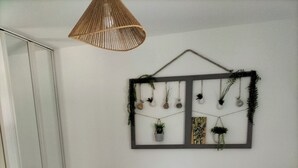 Ein Schlafzimmer mit einem Bett, zwei Nachttischen, einer Hängeleuchte und einer Wandpflanzen-Dekoration.