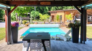 Ein überdachter Außenbereich mit Pool, Tisch und Stühlen.