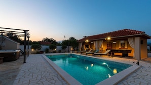 A swimming pool with lounge chairs and a hot tub, surrounded by a stone patio. - Stunning home in Pridraga (Pridraga)