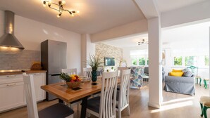 A modern kitchen with a wooden dining table, white chairs, and a fruit basket. - Stunning home in Pridraga (Pridraga)