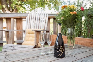 A wooden table with a bottle of champagne, two glasses, and a vase with flowers.