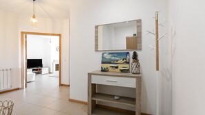Un salon moderne avec une console en bois, un lampadaire blanc et un tableau encadré accroché au mur.