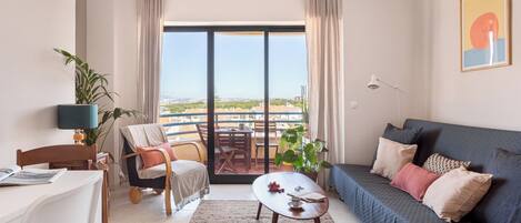 Una sala de estar moderna con un sofá, un comedor y un balcón con vistas.