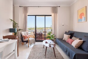 Ein modernes Wohnzimmer mit einer Couch, einer Essecke und einem Balkon mit Blick.