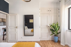 A bedroom with a bed, a mirror, a potted plant, and a wardrobe.