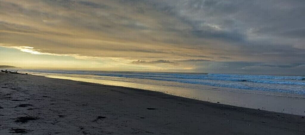 Une plage avec une vaste étendue de sable et un ciel nuageux.