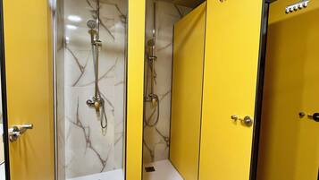 Un baño con puertas amarillas, paredes de mármol y ducha con múltiples cabezales.