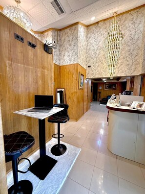 A modern interior with a bar area, a laptop on a table, and a chandelier. - Velvet Hostel (Madrid)