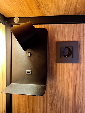 A black electrical outlet with a switch and a USB port on a wooden wall. - Velvet Hostel (Madrid)