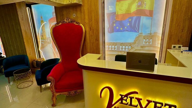 Un mostrador de recepción de hotel con una silla roja y un amplio ventanal que muestra una bandera.