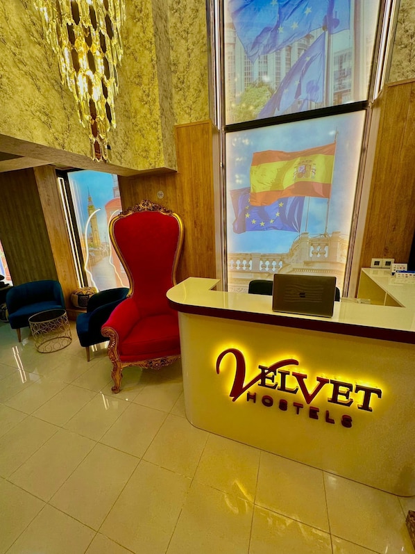 Un comptoir d’accueil d’hôtel avec une chaise rouge et une grande fenêtre donnant sur un drapeau.