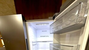 Un refrigerador abierto con múltiples estantes transparentes y un rótulo que dice 'Enfriamiento Integral'.