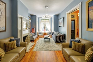 A living room with a fireplace, sofas, a coffee table, and a chandelier. - Historic Georgetown Townhome: Walkable Location! (Washington)