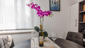 A dining table with two wine glasses, a bottle of Pinot Simi, and a vase with purple orchids. - Beach front home in Vir with WiFi (Vir)