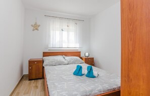 A bedroom with a wooden bed, a nightstand, a starfish decoration, and a window with sheer curtains. - Beach front home in Vir with WiFi (Vir)
