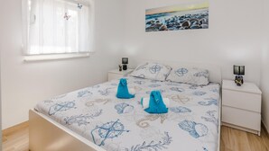 A bedroom with a bed, two bedside tables, a window with curtains, a wall-mounted painting, and a bedside lamp. - Beach front home in Vir with WiFi (Vir)