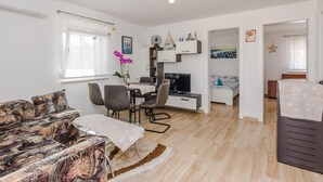 A modern, open-plan living space with a dining area, a sofa, a TV, and a bed. - Beach front home in Vir with WiFi (Vir)