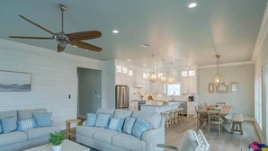 A spacious living room with a ceiling fan, a sofa set, a coffee table, and a dining area with a table and chairs.