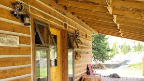Una cabaña de madera con un porche cubierto, una banca y un cartel que dice "5 AD Ranch".