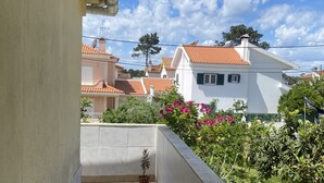 A narrow balcony with tiled flooring, a potted plant, and a view of neighboring houses with red-tiled roofs. - Pavillon 1ER Etage (Setúbal)