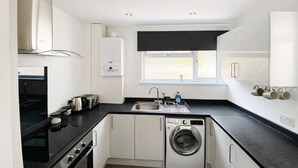 A compact kitchen with a built-in washer, a stove, and a sink. - Emerald Living - Swansea (Swansea)