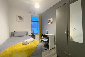 Une chambre à coucher avec un lit, un bureau et une armoire.