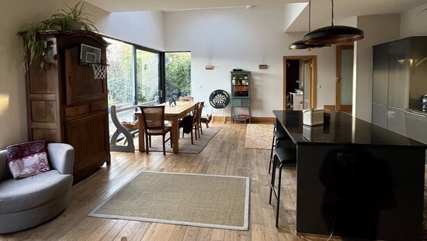 Un vaste espace de vie doté d’un plancher en bois, d’une table à manger et d’un coin cuisine avec un comptoir noir.
