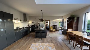 Une cuisine moderne avec des meubles de rangement noirs, une table à manger en bois et une grande fenêtre.