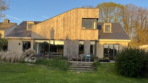 Une maison moderne avec une façade en bois, de grandes fenêtres et un jardin bien entretenu.