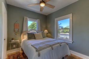 A bedroom with a bed, a ceiling fan, a window, and a nightstand with a lamp. - Cute bungalow close to UofA (Tucson)