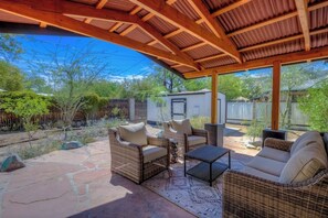 An outdoor patio with wicker furniture, a stone floor, and a covered area with a wooden ceiling. - Cute bungalow close to UofA (Tucson)