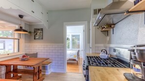 Una cocina moderna con una mesa de madera, una estufa a gas y una cafetera.