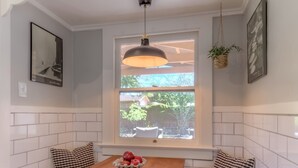Una cocina con gabinetes blancos, una mesa de madera y una ventana con vista a la vegetación.