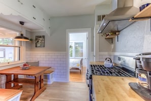Una cocina moderna con una mesa de madera, una estufa y un ventanal.