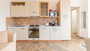 Une cuisine compacte équipée d’une cuisinière, d’un four, d’un four à micro-ondes et d’une machine à café.