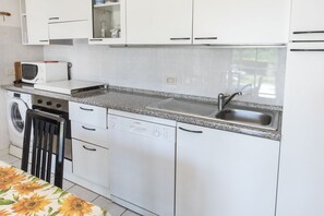 Een koelkast, een oven, een vaatwasser, een eettafel