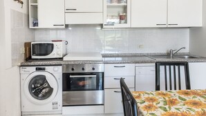 A compact kitchen with a washing machine, microwave, oven, and a sink. - M355 - Marcelli, fully equipped two-room apartment with garden (Marcelli)
