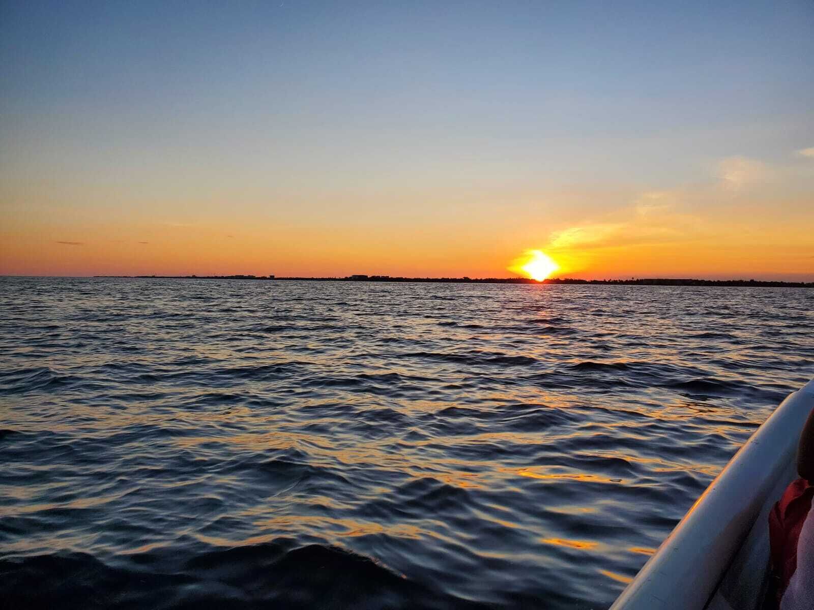 A sunset over a body of water with a distant shoreline.